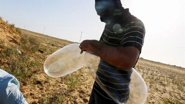 Gaza terrorist prepares incendiary balloon