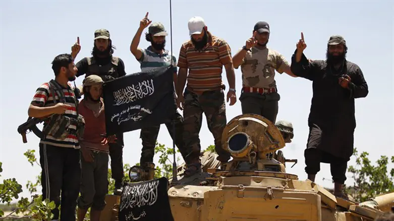 Jabhat al-Nusra members gesture while posing on a tank on Al-Khazan frontline
