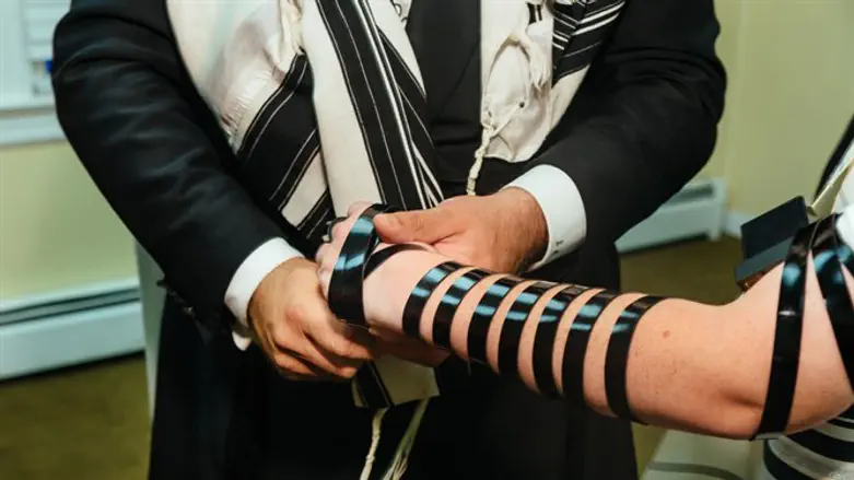Chabad emissary assisting in donning tefillin