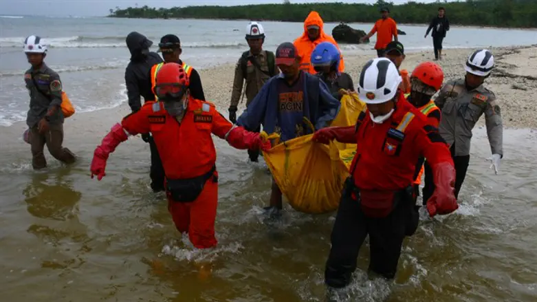 Rescue workers carry a body bag containing the remains of a victim of tsunami