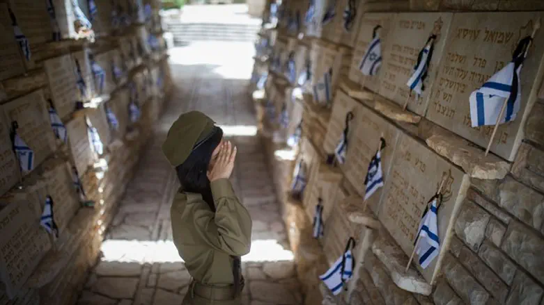 soldiers place Israeli flags on the graves of fallen soldiers in Mount Herzl 