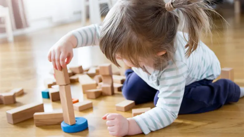 Preschool girl learning to stack blocks (illustrative)