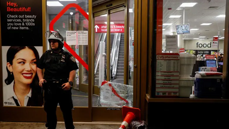 Police officer outside NYC store after it was vandalized following George Floyd's death.