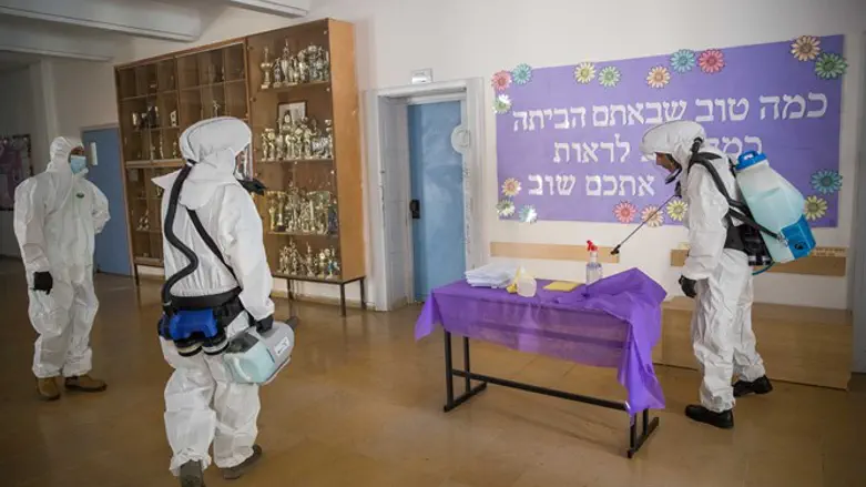Cleaning workers disinfect the entrance to a high school in Jerusalem, June 3, 2020.